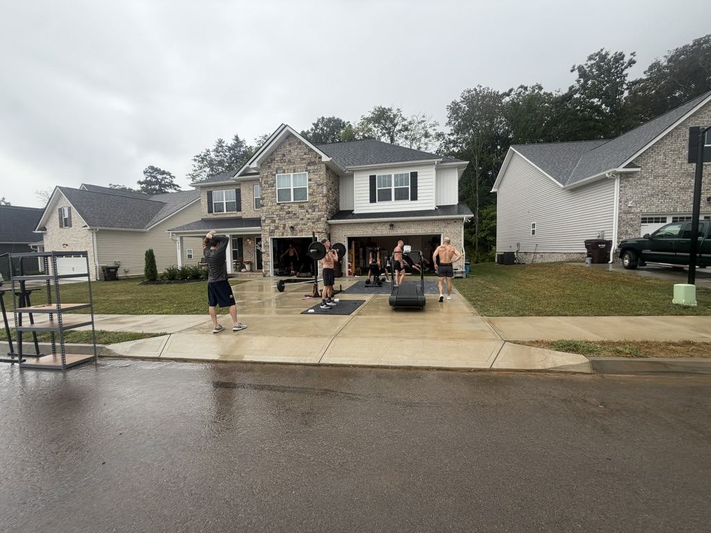 The driveway set up with barbells and a treadmill in the rain